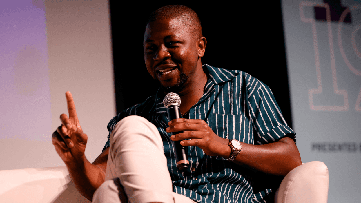 Edafe Okporo speaks onstage while holding a microphone during a public event.