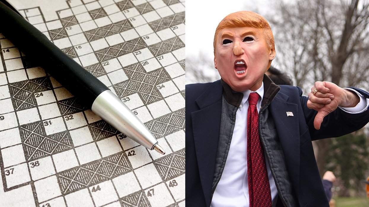 empty crossword puzzle and pen alongside person in donald trump mask giving thumbs down gesture