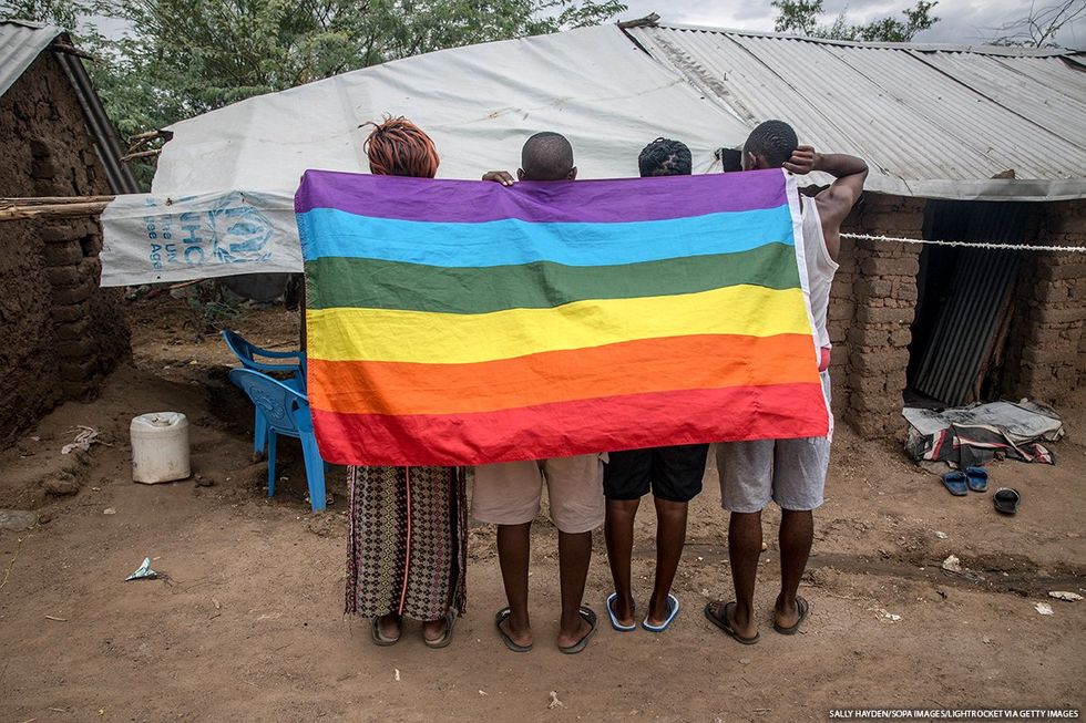Four people holding a pride flag behind their backs