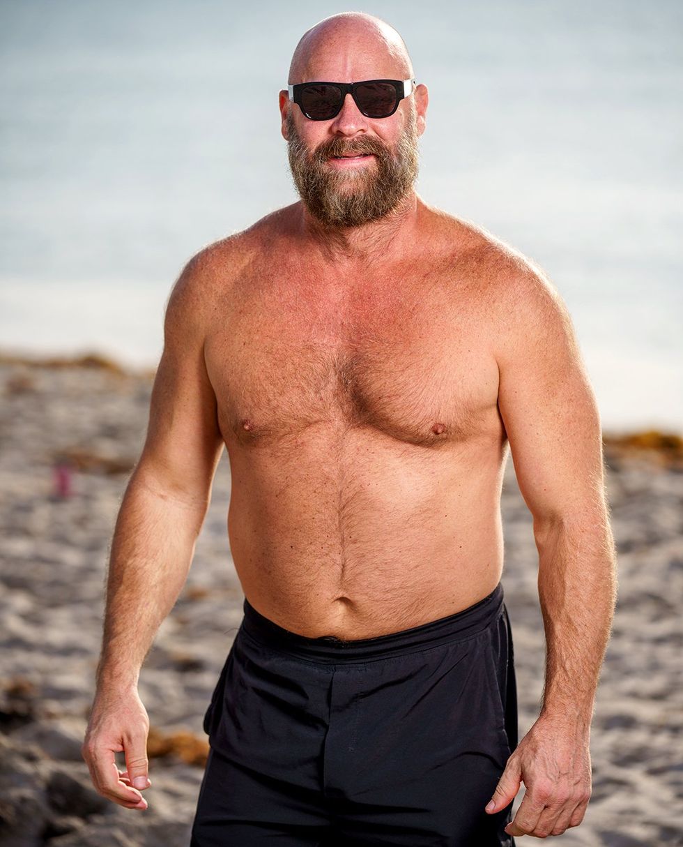 gay bear handsome bearded bald man on beach wearing sunglasses