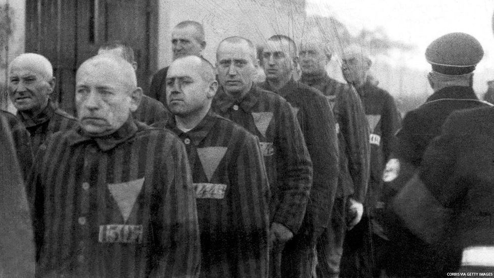 Gay men during the Holocaust, lined up wearing prison jumpsuits with upside-down pink triangles (the photo is black and white)