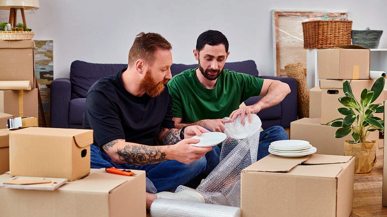 gay queer couple packing dishes in moving boxes