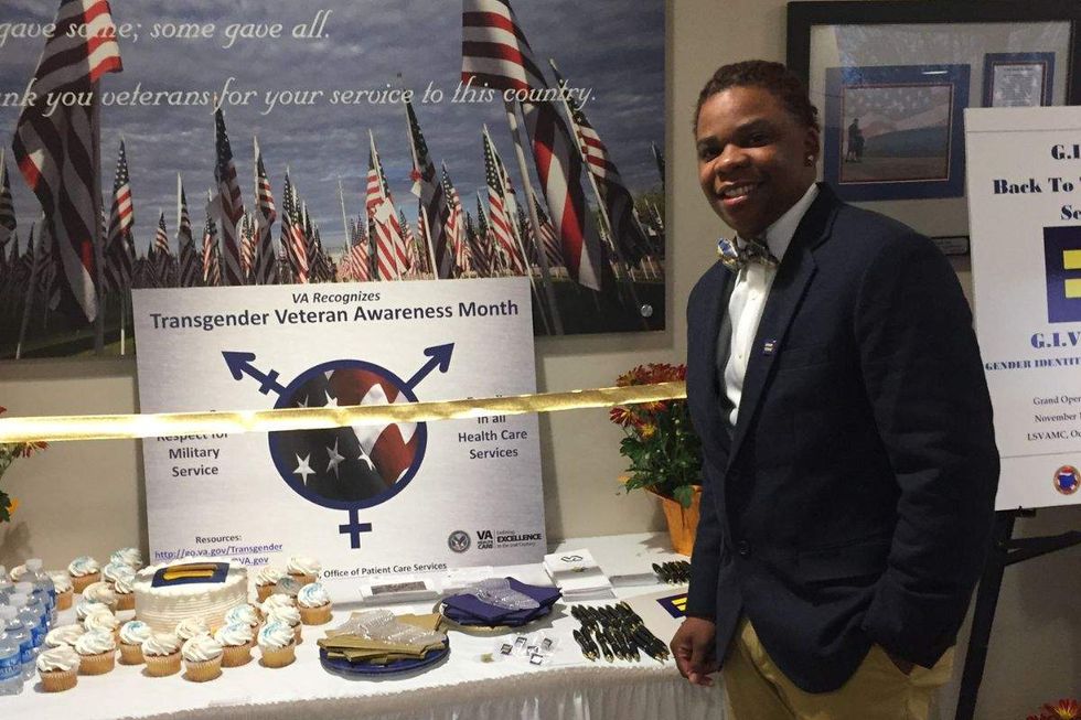 gio santiago at a table with a sign that states va recognizes transgender veteran awareness month