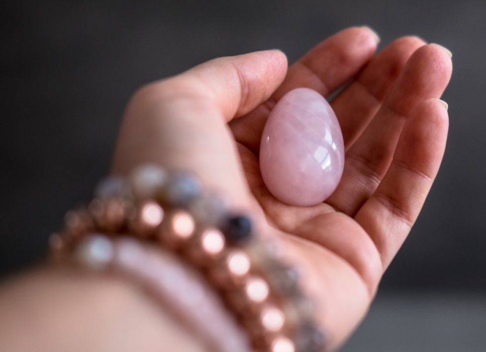 hand holding egg shaped rose quartz crystal