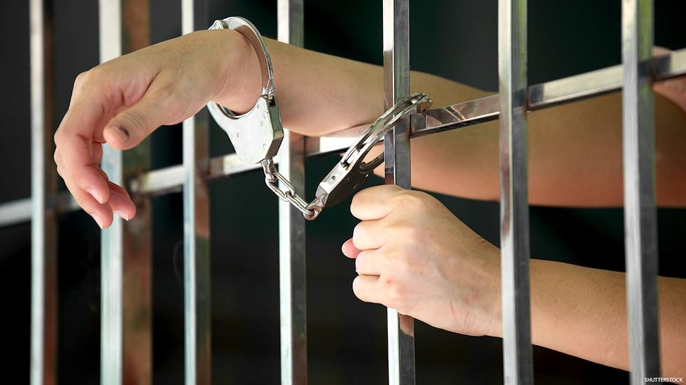 Handcuffed hands behind bars
