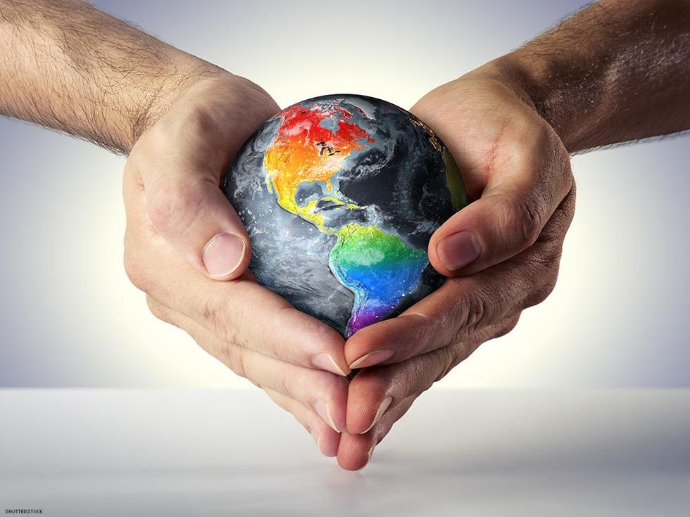 hands holding globe with rainbow land masses
