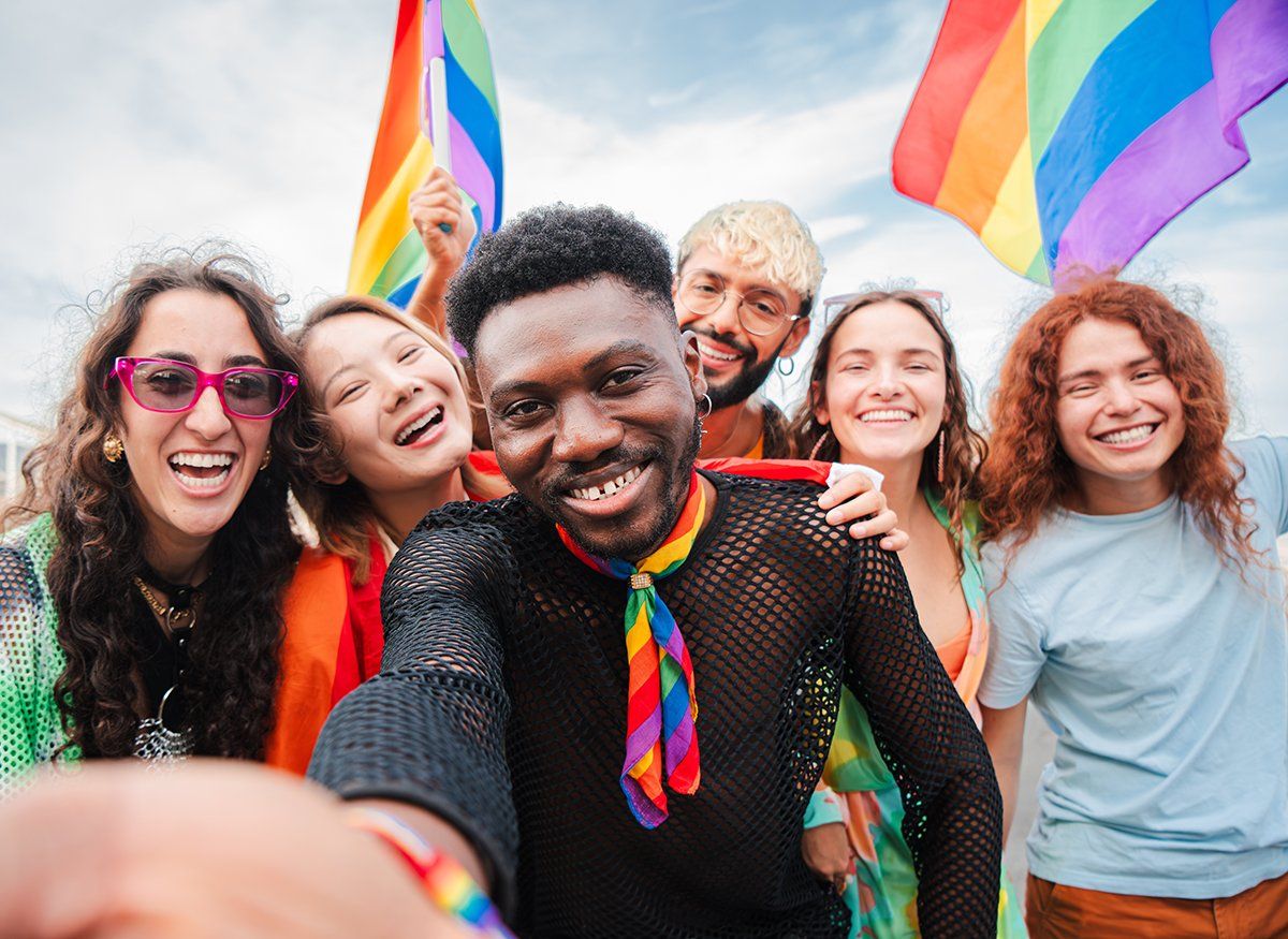 Happy multiracial young adult people having fun rainbow flags