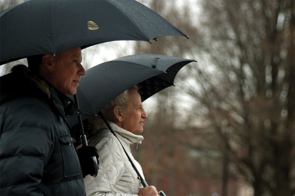 Harper Steele and Will Ferrell standing in the rain with umbrellas