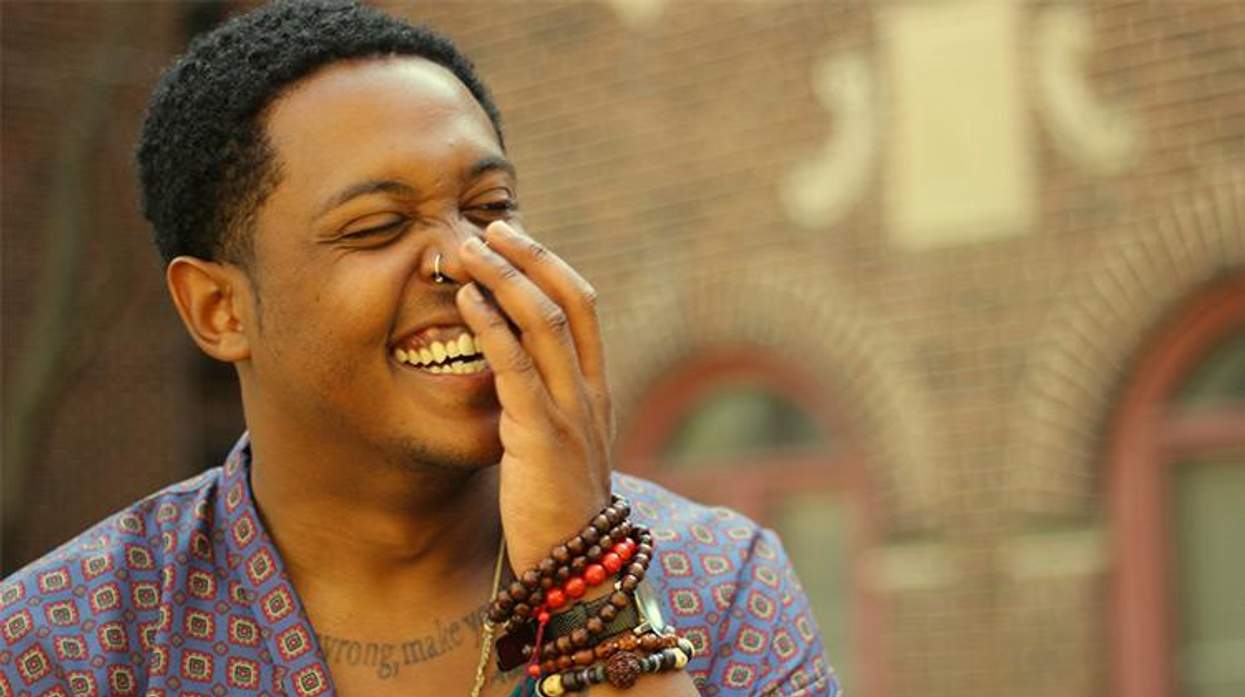 Headshot of Danez Smith, a black queer male poet, laughing and looking toward side of frame