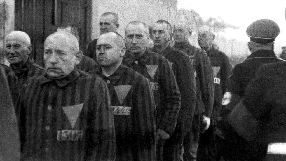 holocaust prisoners in striped uniforms bearing triangular badges on parade in Sachsenhausen Concentration Camp near Berlin Germany 19th December 1938 while Nazi officers stand guard