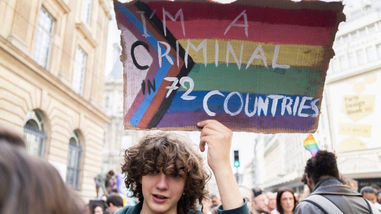 i'm a criminal in 72 countries sign with lgbtq pride flag background