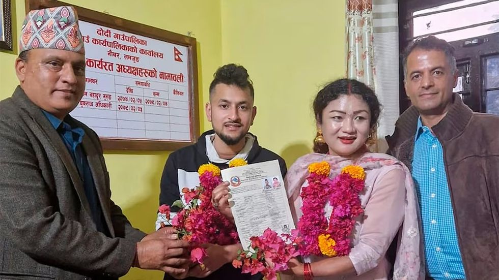 In this handout photo provided by Sunil Babu Pant (far right), same-sex couple Surendra Pandey, second left, and Maya Gurung, who got married six years ago, pose for a photograph with their marriage registration certificate at Dorje village council office, located in the mountains west of the capital Kathmandu, Nepal, Wednesday, Nov. 29, 2023. The couple became the first in the nation to receive official same-sex marriage status.