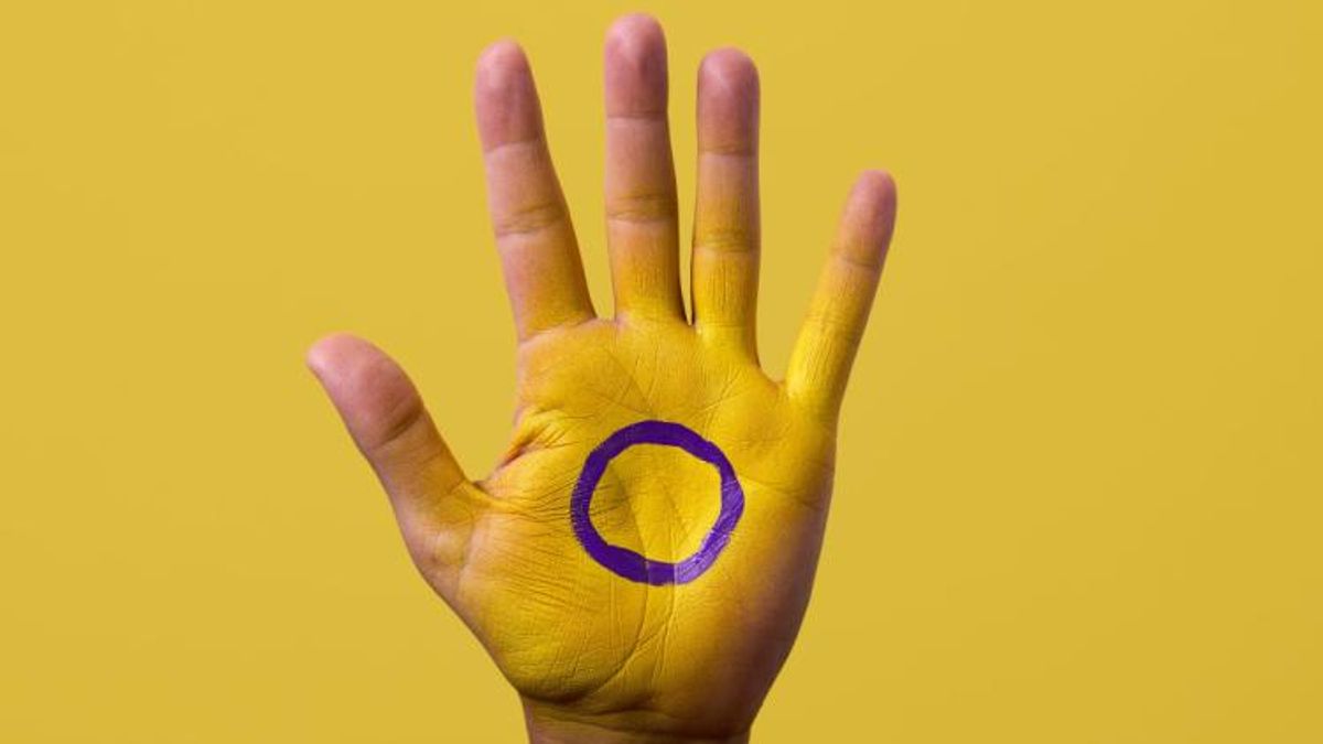 Intersex symbol on a hand with yellow backdrop