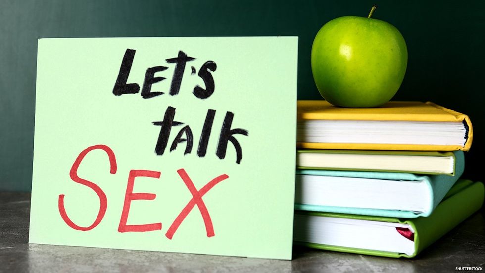 Let’s talk sex sign next to books and an apple