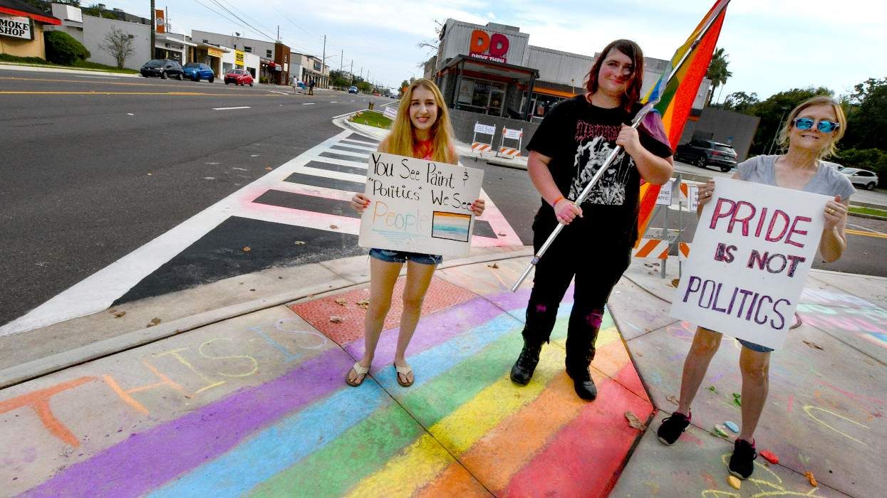 LGBTQIA groups protest with rainbow signs flags chalk at the Orlando Florida intersection of Pulse Nightclub memorial