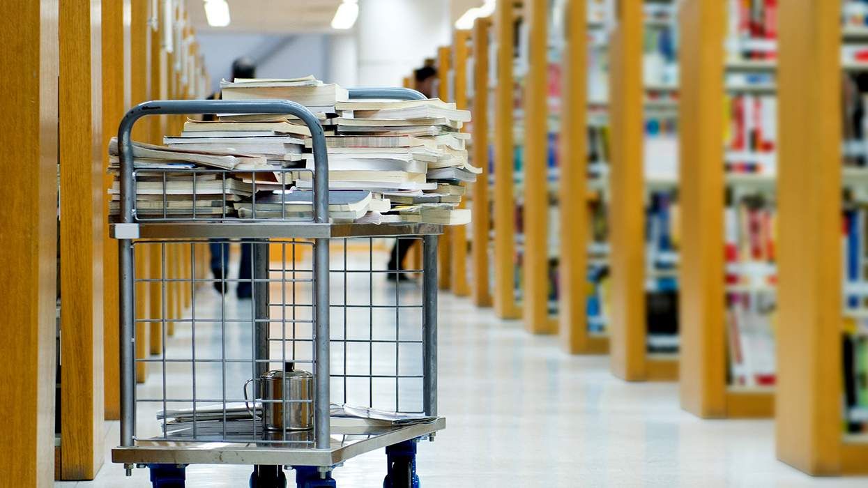 library books on a cart among bookshelves