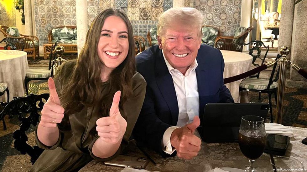 Libs of TikTok owner Chaya Raichik and former president Donald Trump smiling and gesturing thumbs up while seated at a round table at Mar-a-Lago