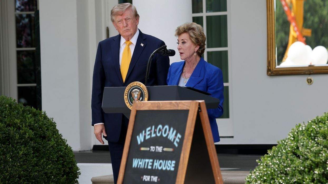 linda mcmahon speaking at a lectern as donald trump looks on