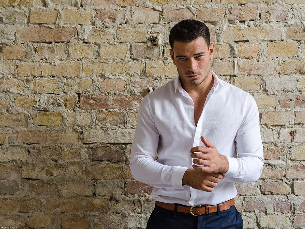 man buttoning his sleeve brick wall background