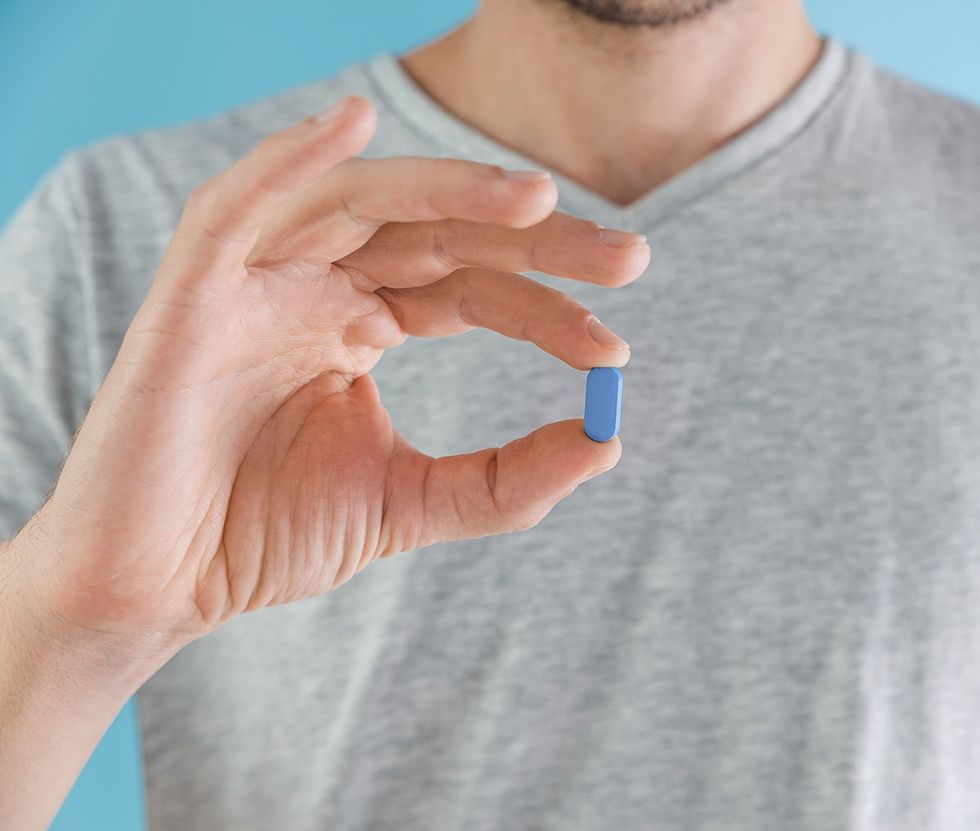 man holding blue prep HIV medication pill