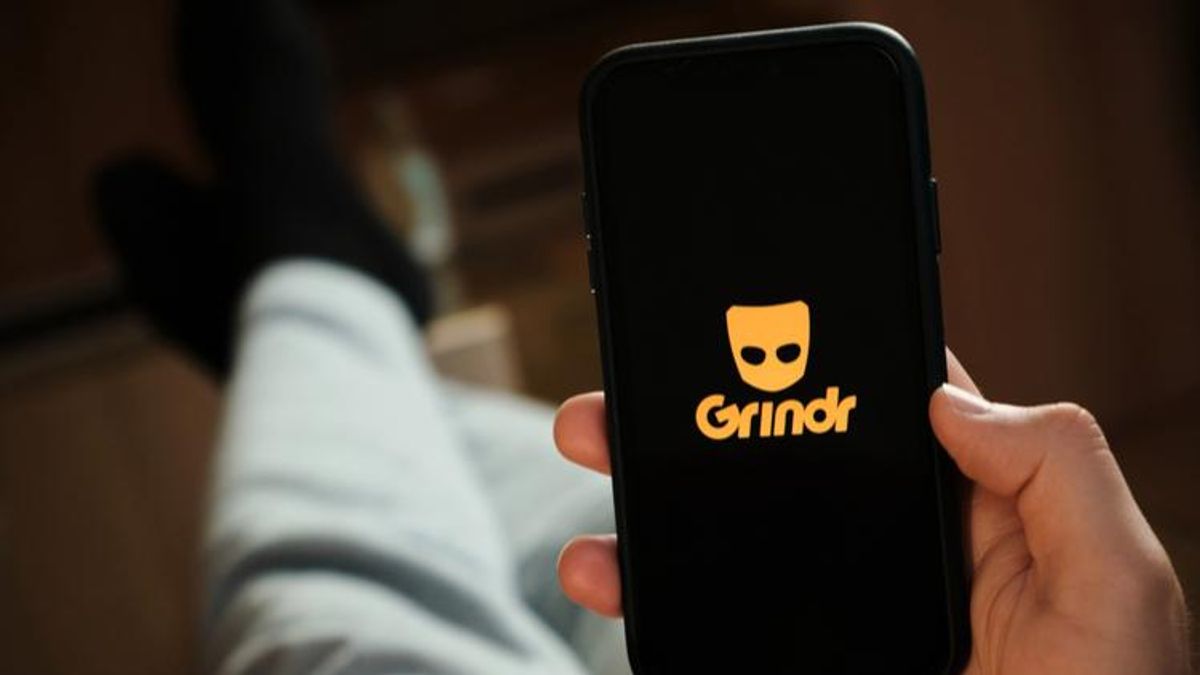 man holding smartphone with grindr logo