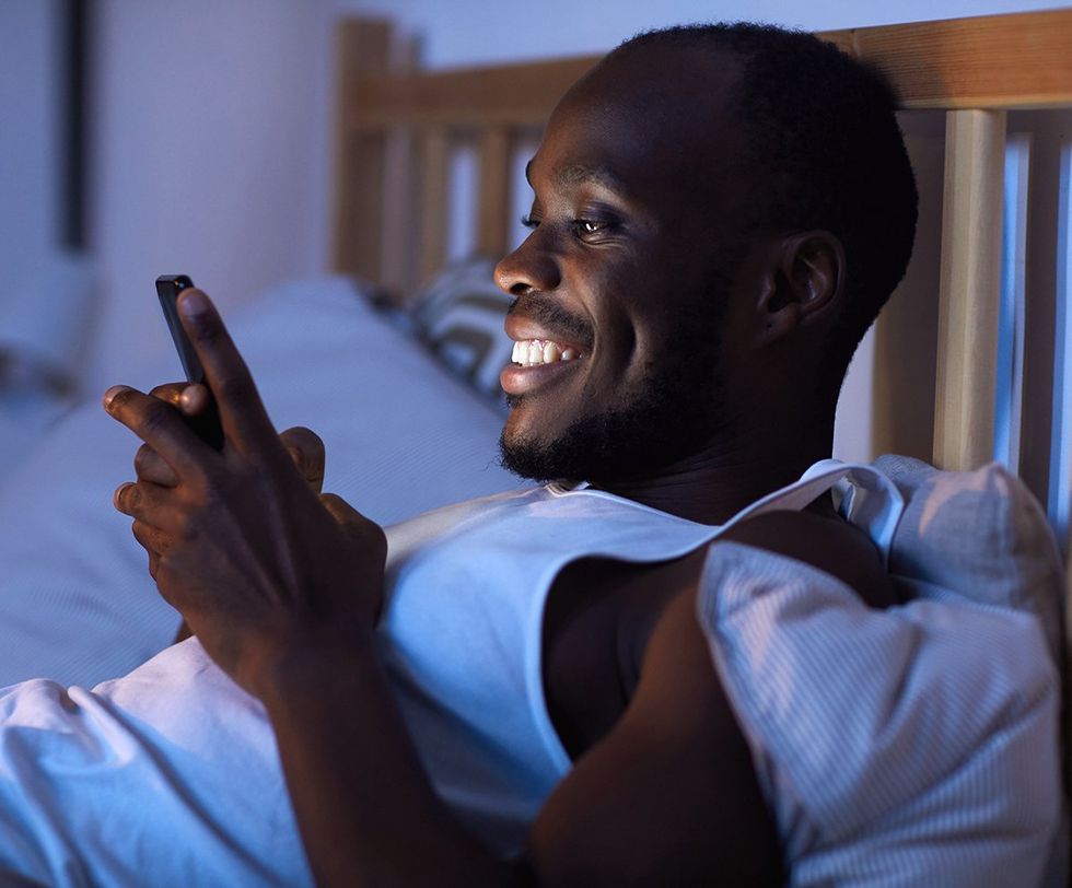 man in bed scrolling on cellphone