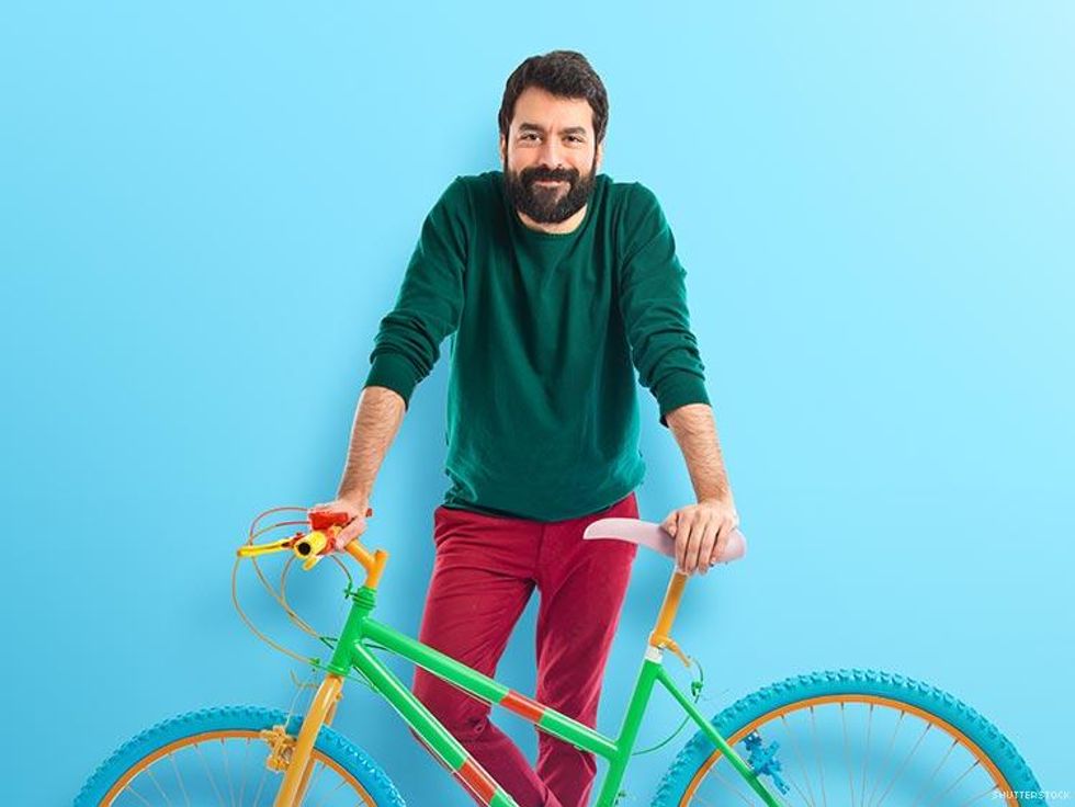 man in colorful outfit with bicycle against a blue background