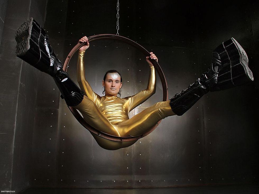 man in gold sitting an aerial hoop