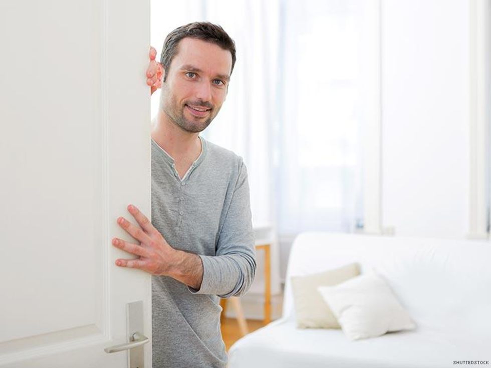 man in gray shirt half behind bedroom door