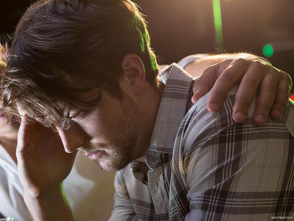 man in plaid shirt with hand on his shoulder