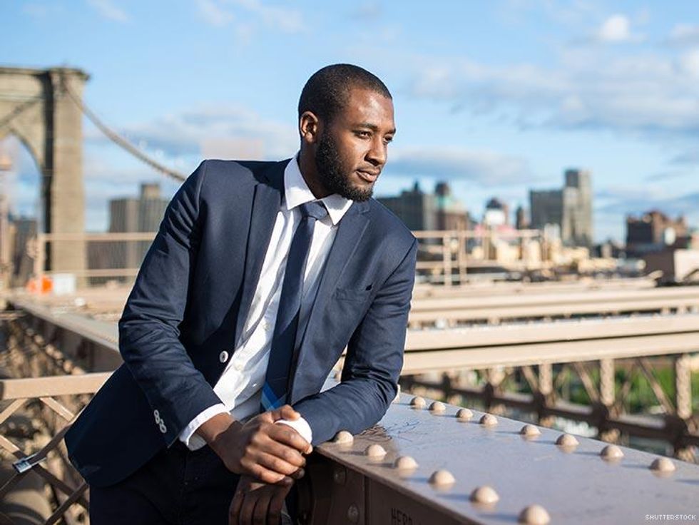 man in suit with brooklyn bridge behind him
