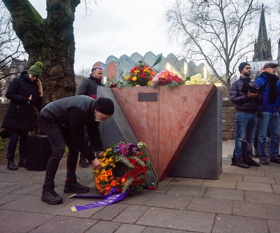 man places wreath pink triangle monument memorial to gay and lesbian holocaust victims