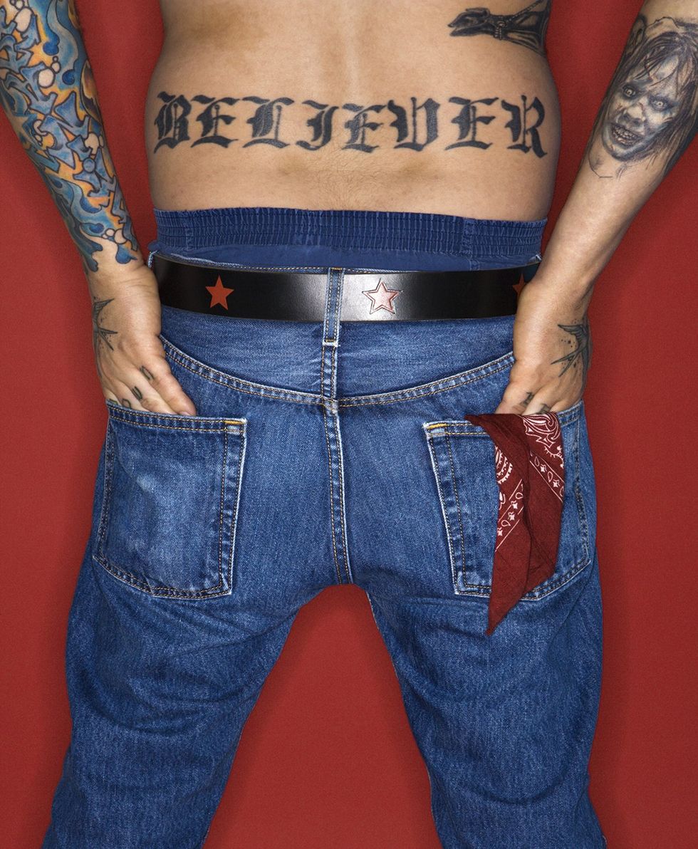 man with back tattoo wearing jeans with a dark red bandana in back pocket