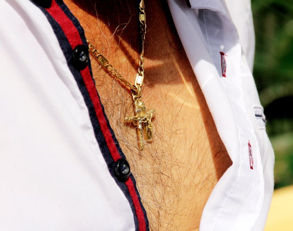 man with hairy chest open button shirt wearing gold crucifix necklace