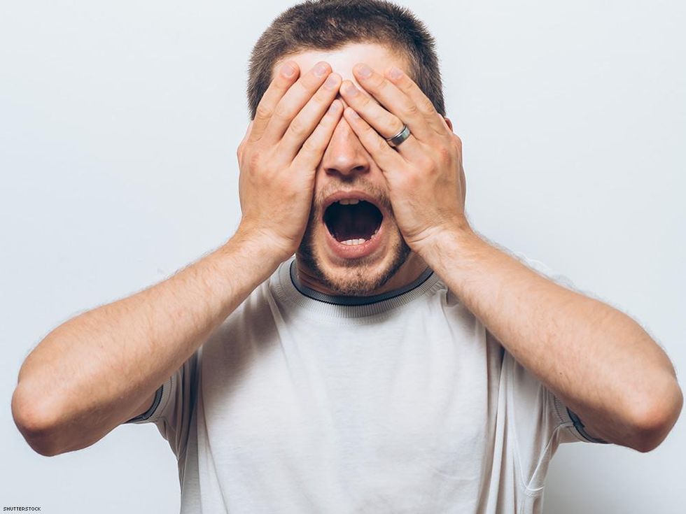 man with hands over eyes and mouth open