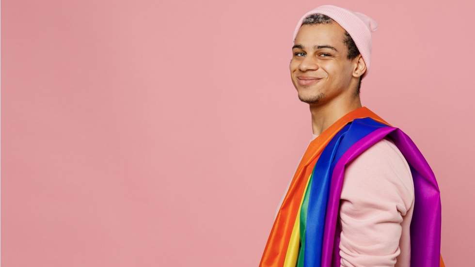man with rainbow flag wrapped over his shoulder