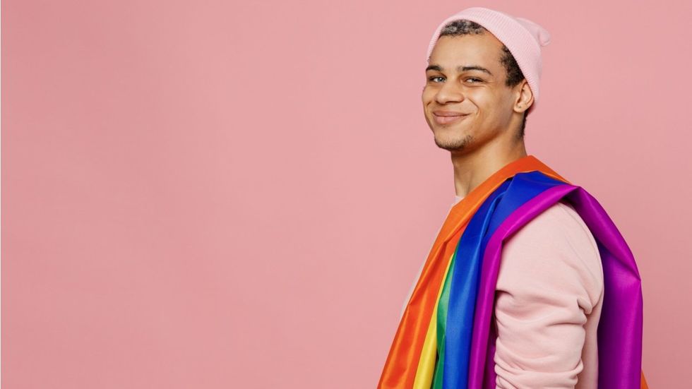 man with rainbow flag wrapped over his shoulder