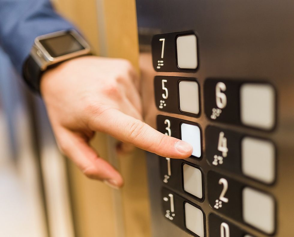 man with smart watch pressing elevator button