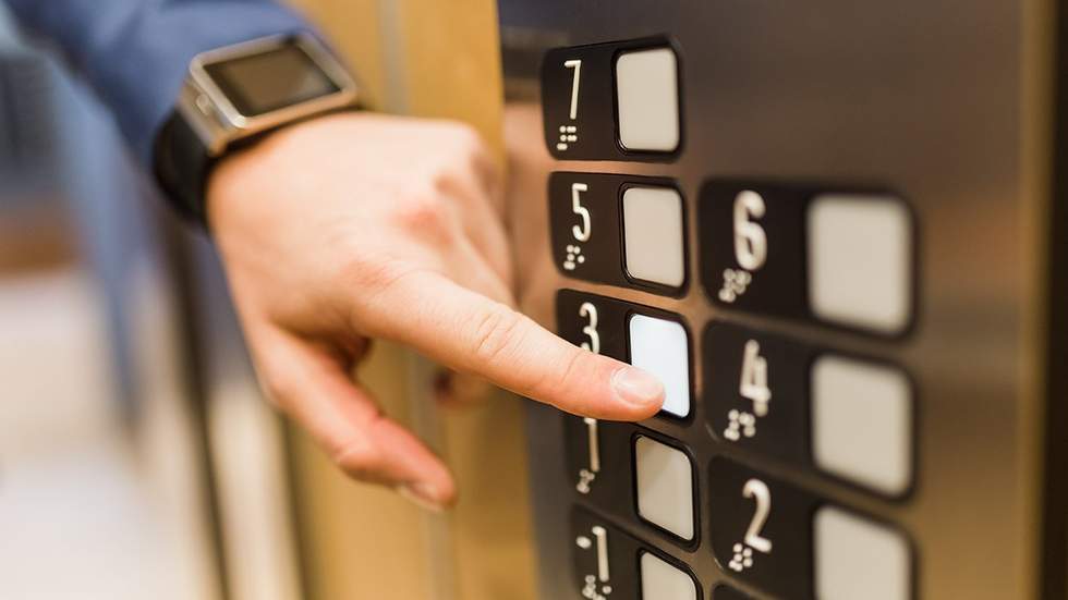 man with smart watch pressing elevator button