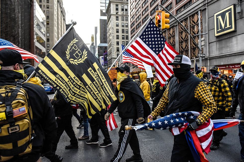 Members of the Proud Boys march in Manhattan against vaccine mandates waving flags