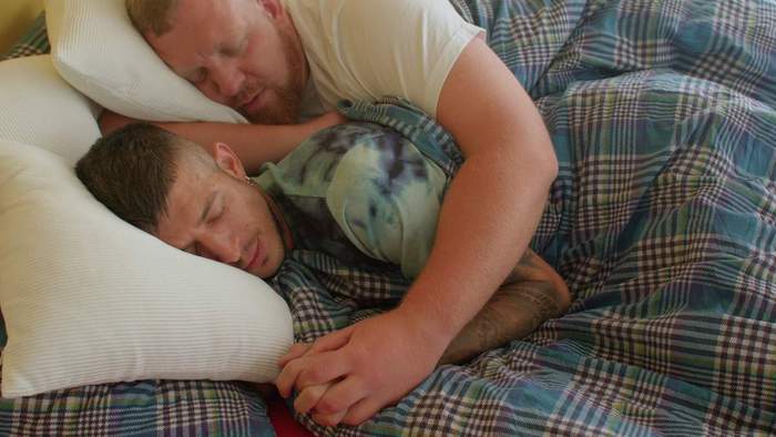 Men cuddle in bed