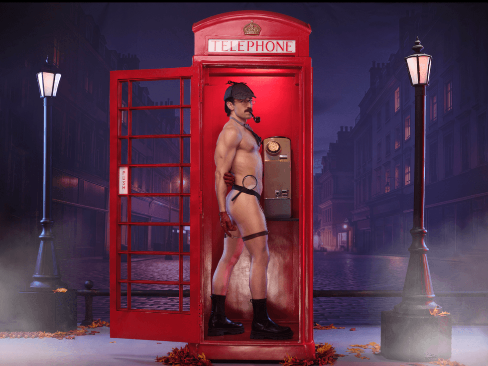 Michal Kolaczkowski dressed as a sultry Sherlock Holmes stands inside a red London phone booth, wearing a detective cap and holding a pipe, with a moody nighttime street backdrop