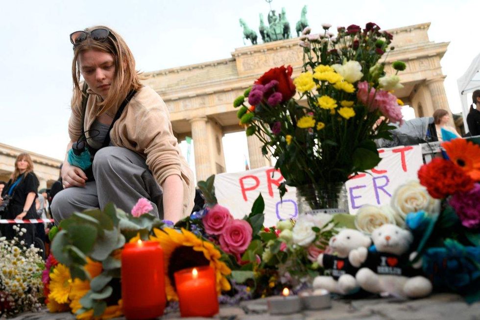 mourner placing candles and flowers near the brandenburg gate