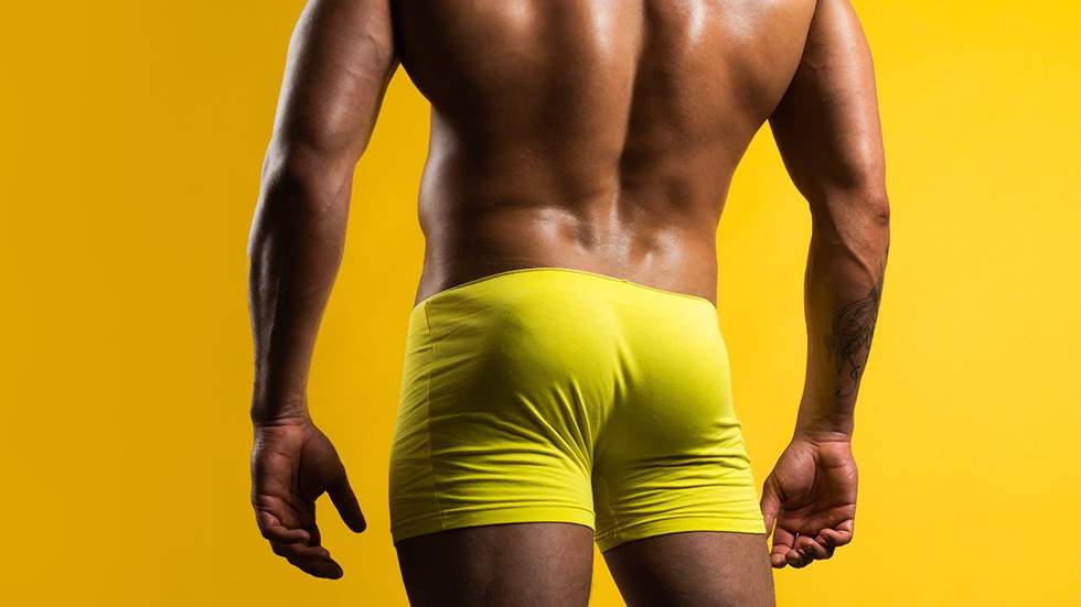 muscle man in yellow shorts from behind