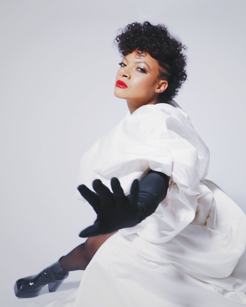 Musician Allison Russell in white dress and black gloves and black vinyl boots
