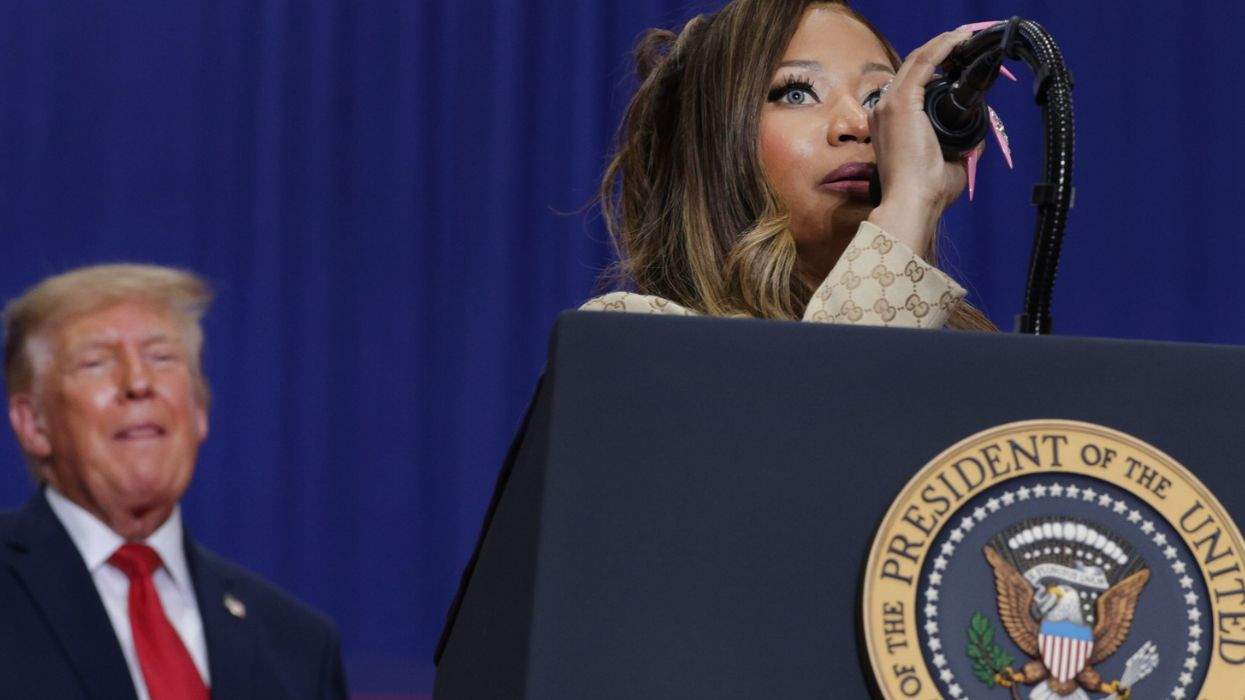 nicki minaj speaking at a podium with donald trump behind her