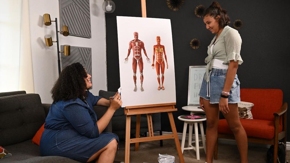 Parent and her daughter discuss anatomy with charts behind them