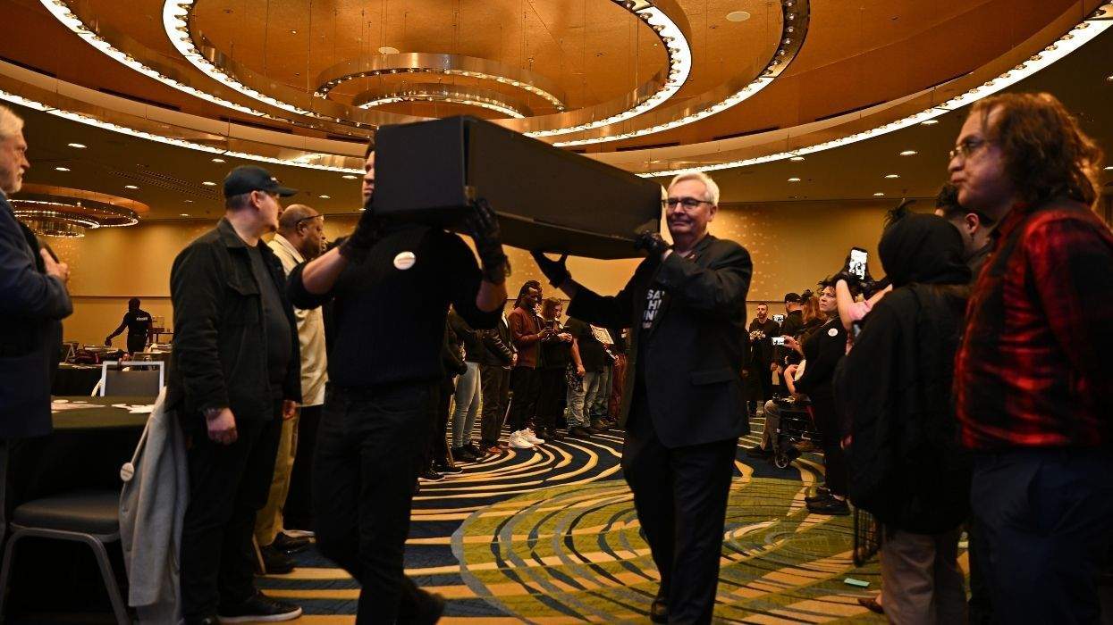 people carrying a black false coffin
