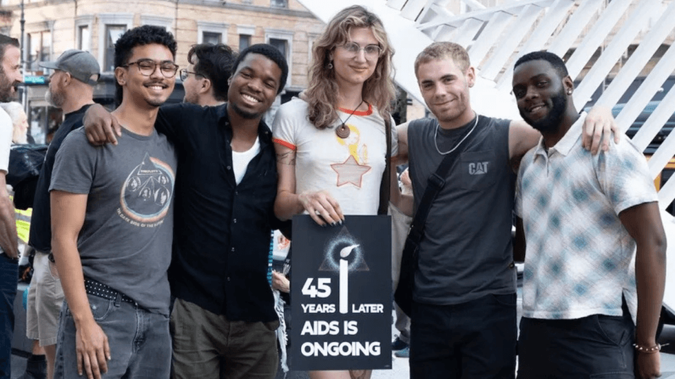 People gather around a sign that reads "45 years later AIDS is ongoing."