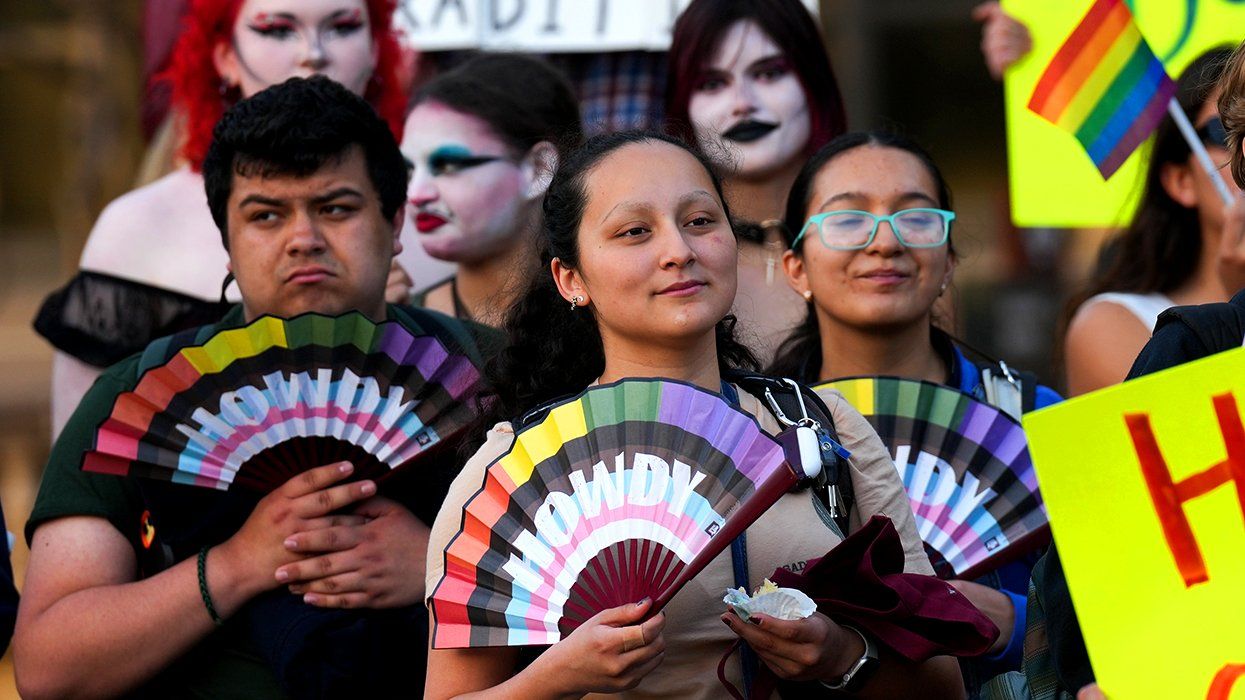 people hold rainbow HRC Howdy fans during a protest sponsored by Texas AM University Queer Empowerment Council Day of Drag protest on campus in College Station